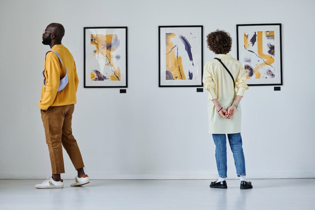 two people in an art gallery looking at pieces.